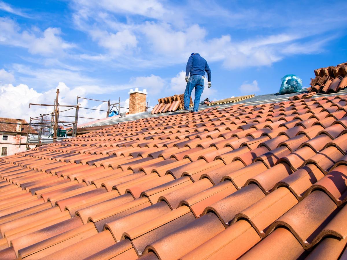Couvreur posant des tuiles sur une toiture en cours de rénovation